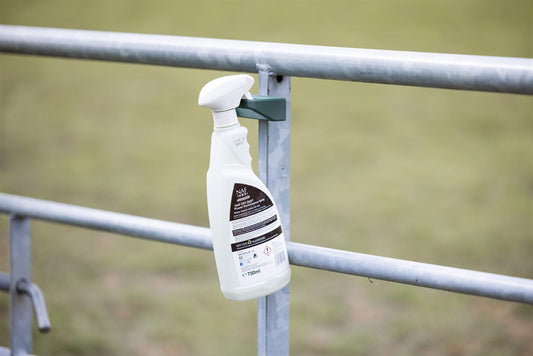 Fly spray bottle in a SnapTack magnetic spray holder on a field gate