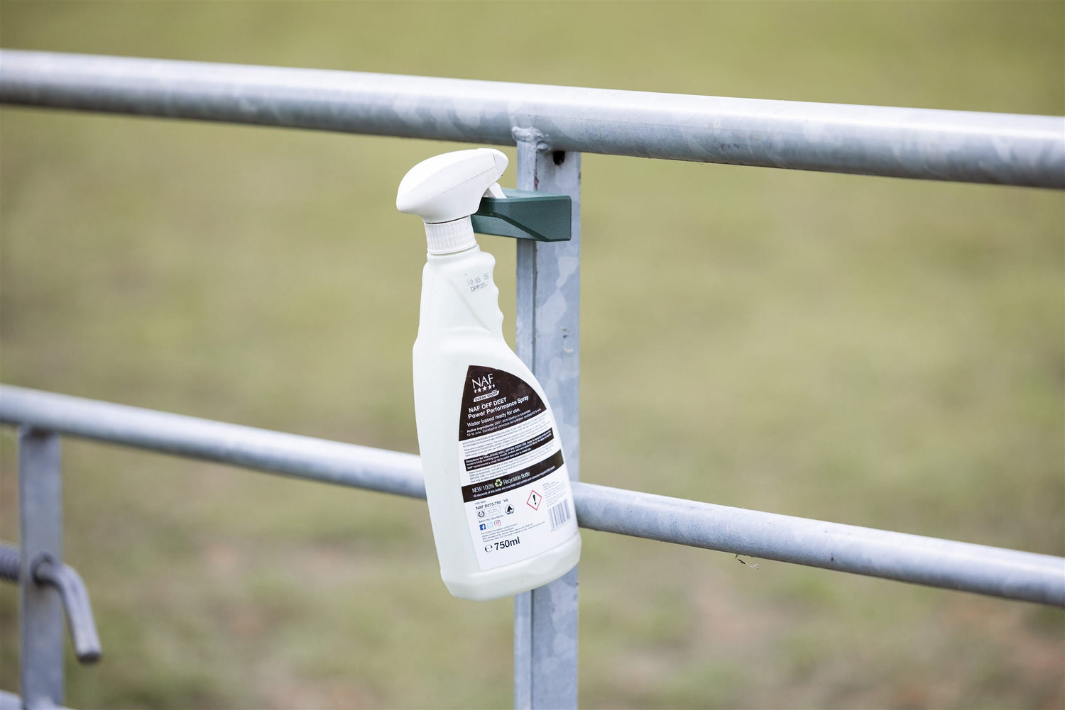 Fly spray bottle in a SnapTack magnetic spray holder on a field gate