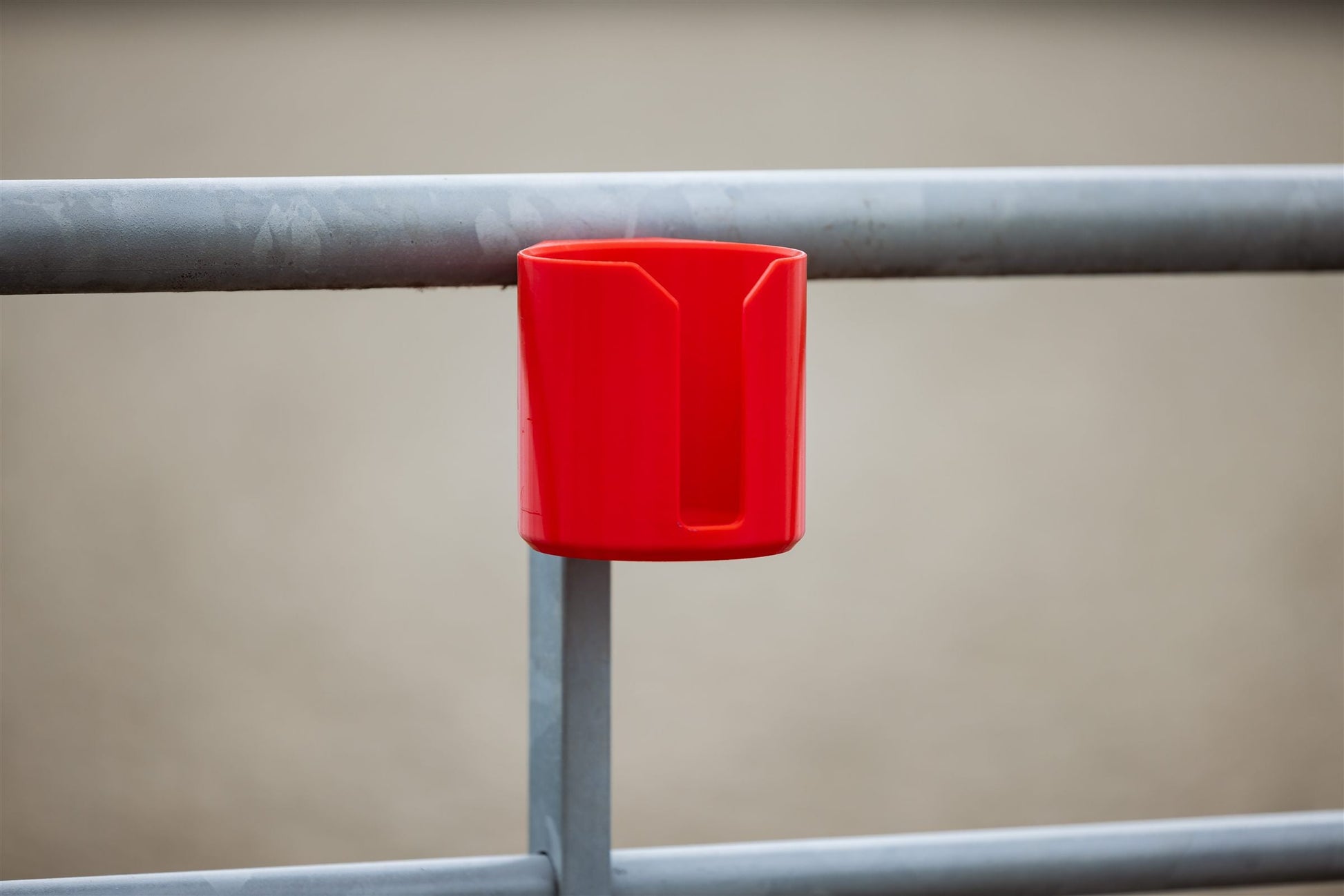 Red SnapTack magnetic cup holder snapped onto a metal gate