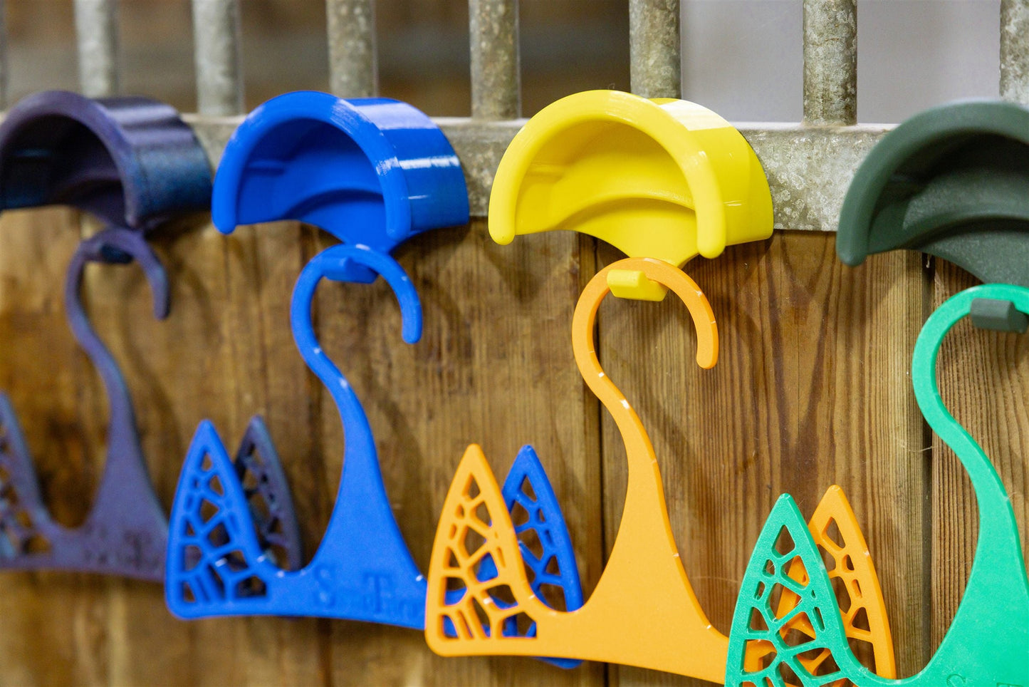 SnapTack magnetic bridle holders with hooks in bright colours on a stable wall