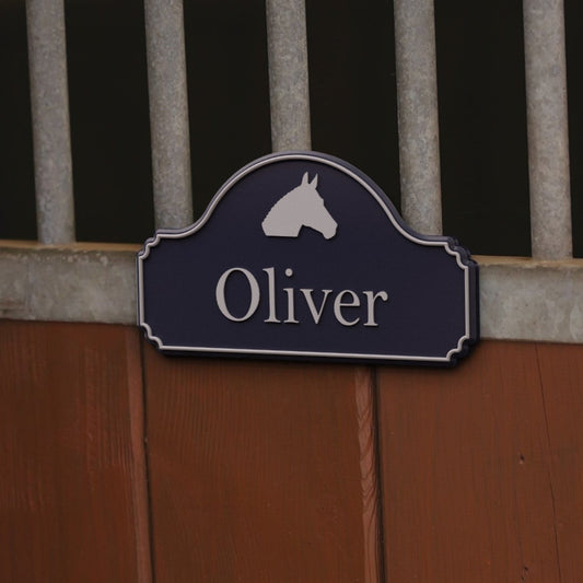 Render: SnapTack magnetic stable door sign with a horse head picture and the name Oliver, midnight and silver, on a stable door's metal band